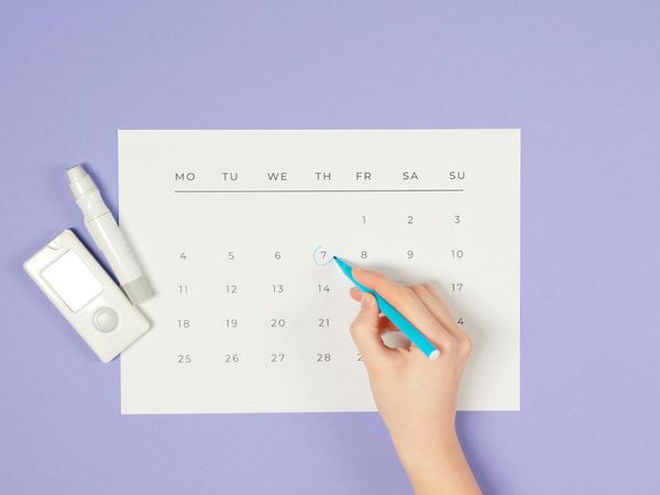 A calendar with marked dates and a simple cup of tea, representing a daily routine.